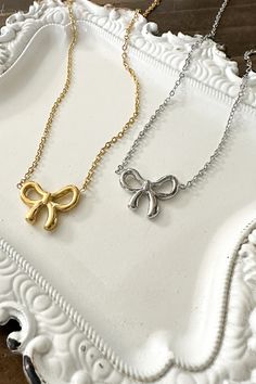 Get ready to amp up your style with our adorable Dainty Bow Necklace! Wrap yourself in charm and sweet simplicity with this gorgeous necklace featuring a tiny bow pendant. Timeless Design: The delicate bow design adds a timeless and feminine touch to your style. High-Quality Stainless Steel: Crafted with precision and durability in mind, our necklace is made from high-quality stainless steel, ensuring longevity and resistance to tarnish. Versatile Finishes: Choose between the classic elegance of Delicate Bow Necklace For Party, Adjustable Necklace With Decorative Bow For Gifts, Adjustable Necklace With Decorative Bow As Gift, Chic Ribbon Necklace Perfect For Gifts, Chic Ribbon Necklace For Gift, Chic Bow Necklace For Gift, Dainty Silver Necklace With Bow, Dainty Adjustable Bow Necklace, Dainty Adjustable Necklaces With Bow