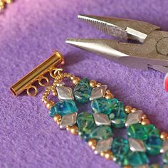 a pair of scissors and some beads on a purple surface with other items in the background