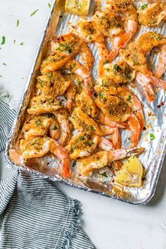 a pan filled with cooked shrimp and lemon wedges