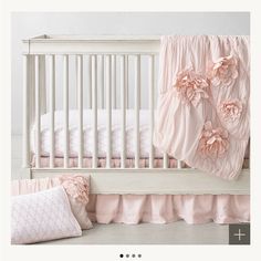 a white crib with pink bedding and pillows