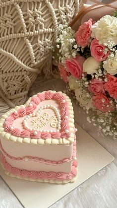 a heart shaped cake sitting on top of a table next to a bouquet of flowers