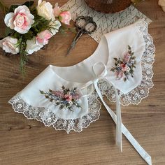 two pieces of white lace with flowers on them next to some scissors and other items