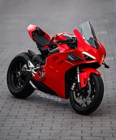 a red motorcycle parked on top of a brick road