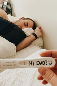 a man laying in bed with a thermometer attached to his arm that says hi dad