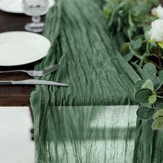 the table is set with silverware and green linens, along with white roses