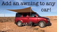 a red car parked in the desert with an awning over it