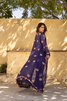 A stunning and unique addition to your ethnic wear collection. The set features a beautiful purple jacket crafted from luxurious georgette fabric and adorned with intricate embroidery and ruffled edges, creating a sophisticated and feminine look. It’s paired with a matching hand pleated crop top that features a delicate floral print, adding a touch of ethereal beauty to the overall ensemble. The flowing pants are adorned with sequin embroidery, creating a striking and elegant look that’s perfect Bohemian Long Sleeve Georgette Sets, Purple Anarkali Kurta With Floral Embroidery, Eid Georgette Front Open Dupatta, Eid Front Open Georgette Dupatta, Front Open Georgette Dupatta For Eid, Purple Floral Embroidered Georgette Traditional Wear, Purple Georgette Kurta With Long Sleeves, Bohemian Kurta With Floral Embroidery In Georgette, Purple Long Sleeve Georgette Kurta