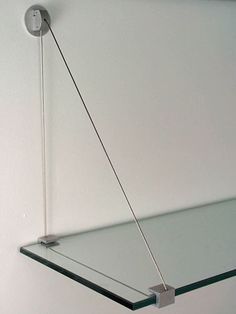 a glass shelf hanging from the ceiling with a light on it's end and a cord in front of it