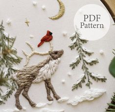 a close up of a embroidery pattern on a hoop with a bird and pine trees