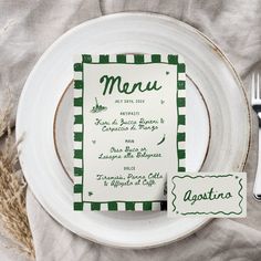 a white plate topped with a green menu next to a fork and knife on top of a table