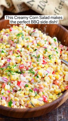 a wooden bowl filled with corn salad on top of a table