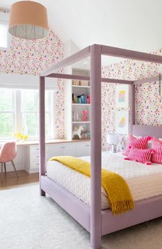 a white bed with pink and yellow pillows on top of it next to a window