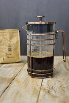 a coffee pot filled with liquid sitting on top of a wooden table