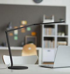 an open laptop computer sitting on top of a white desk next to a black lamp