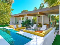 an outdoor living area with couches and a swimming pool in front of a house