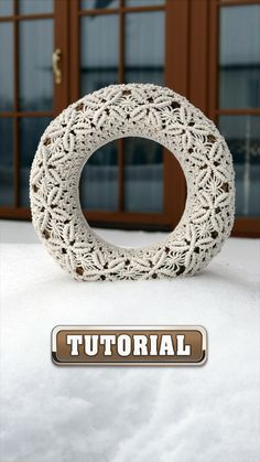 a knitted wreath sitting on top of snow covered ground next to an open door