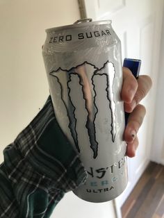 a person holding up a monster energy drink