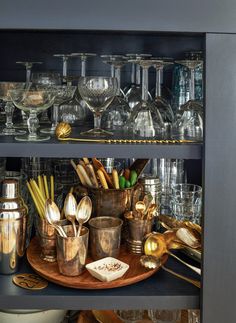 the shelves are filled with glasses, silverware and other kitchen utensil items