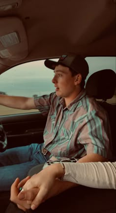 a man sitting in the driver's seat of a car with his hand on the steering wheel