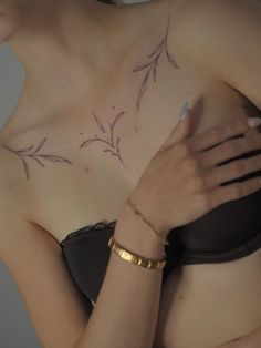 a woman wearing a bra with tattoos on her chest and arm around her waist,