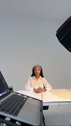 a woman sitting at a desk in front of a laptop computer with an umbrella behind her