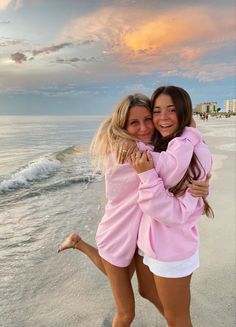 two girls hugging each other on the beach