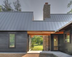 a house with a metal roof and stone pillars