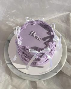 there is a purple cake with white ribbons on the plate and it says, i love thee