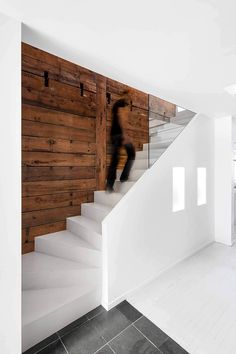 a person walking up some stairs in a room with white walls and wood paneling