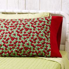 a red and green pillow sitting on top of a bed next to a white headboard