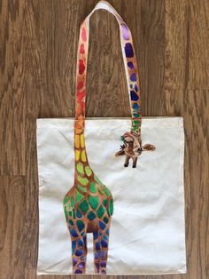 a giraffe painted on a white tote bag sitting on top of a wooden floor