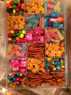 a plastic container filled with lots of different types of candies and candy bars on top of a table