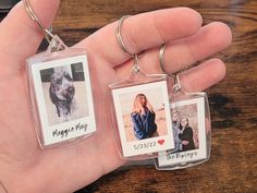 two keychains with pictures of people and a dog on them are being held in someone's hand