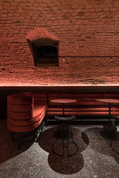 two red chairs sitting next to each other in front of a brick wall