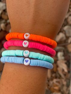 a woman's arm with four different colored bracelets on top of each other