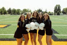 four cheerleaders pose for a photo on the football field