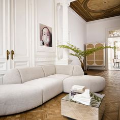 a large white couch sitting in a living room next to a table and potted plant