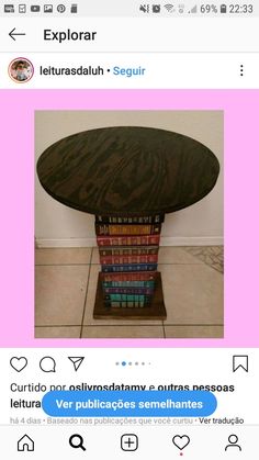 a table with books stacked on top of it in front of a white wall and pink background