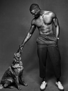 a man is holding his dog's paw while standing in front of a black and white photo