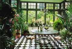 a dining room with black and white checkered flooring, potted plants on the table