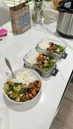 three bowls filled with rice, broccoli and other food on a counter top