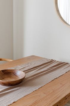 a wooden bowl sitting on top of a table next to a mirror in a room