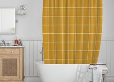 a bath tub sitting next to a white sink under a bathroom window covered in yellow plaid shower curtain