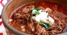 a close up of a bowl of food with meat and vegetables in it on a table