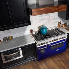 a blue stove top oven sitting inside of a kitchen next to black cabinets and counter tops