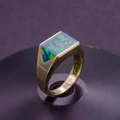 Make a statement with this stunning solid gold signet ring, featuring a large lab-made black opal inlay that shimmers with a captivating iridescence. The inlay is expertly crafted and set into the gold with precision, resulting in a bold and unique design that's sure to turn heads. Unlike cheap hollow or plated rings, this signet ring is crafted from solid gold throughout for a luxurious and high-quality finish that's built to last. Perfect for men who appreciate fine jewelry and bold design, th Modern 14k Gold Opal Ring With Polished Finish, Modern Opal Ring In 14k Gold With Polished Finish, Modern Formal Opal Jewelry, Formal Opal Ring With Polished Finish, Opal Ring For Men, Customization Ideas, Jewellery Boutique, Opal Band, Mens Rings Fashion