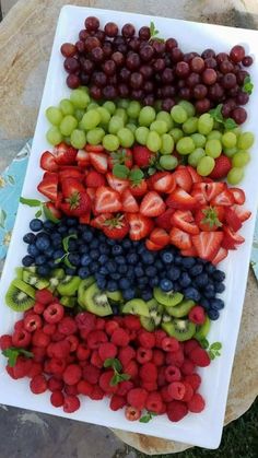 grapes, strawberries, and kiwis are arranged on a platter to be eaten