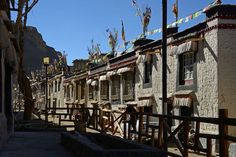 a row of buildings with flags hanging from the roof and windows in front of them