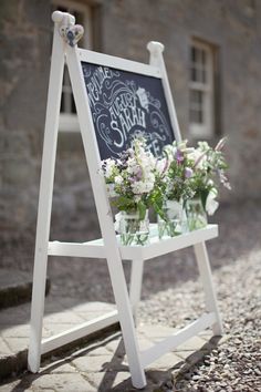 the wedding sign is decorated with flowers and chalkboard