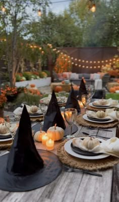 a wooden table topped with black and white plates covered in witches hats next to candles